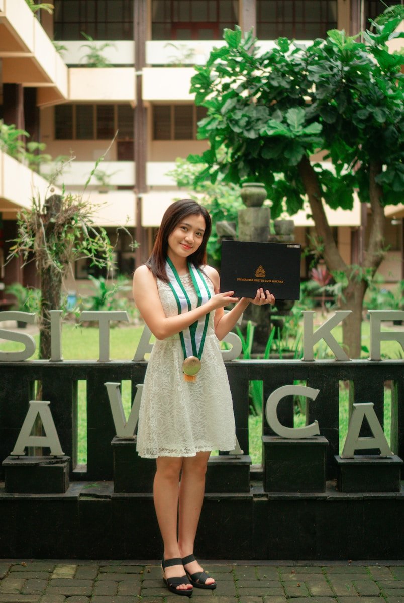 a woman in a white dress is holding a laptop